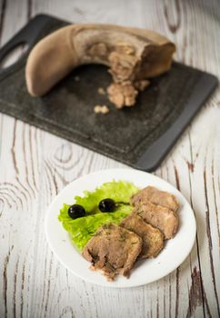 boiled beef tongue sliced in a plate on a wooden table