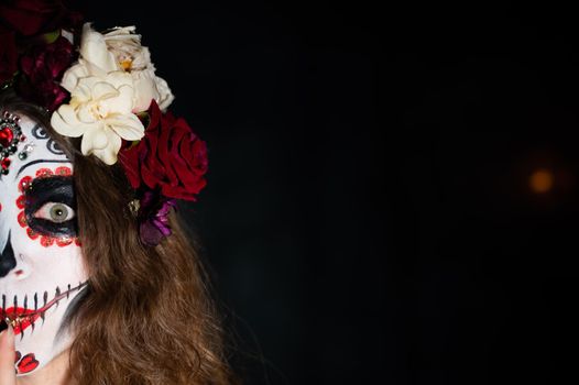 Woman in santa muerte makeup on a black background. Girl wearing traditional mexican holy death costume for halloween. Copy space.