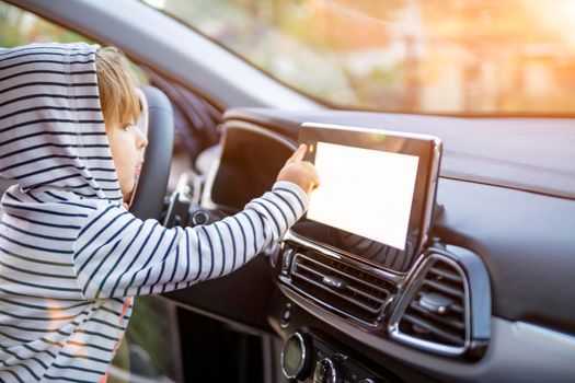 curious toddler girl holding, touching, and turning a car mnultiedia touch screen player button. empty white screen