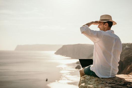 freelancer businessman working remotely on laptop at the beach near the sea