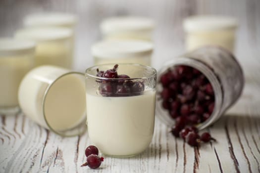 Homemade sweet yogurt with frozen berries in a glass on the table