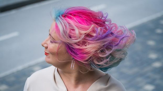 Close-up portrait of curly Caucasian woman with multi-colored hair. Model for hairstyles.