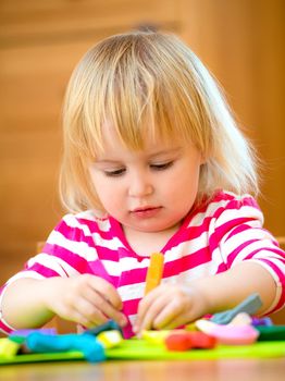 Little girl playing with plasticine at home