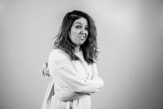 Close-up portrait of insane woman in straitjacket on white background. Monochrome