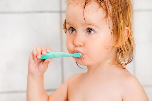 Dental hygiene. Cute baby brushing teeth in bathroom