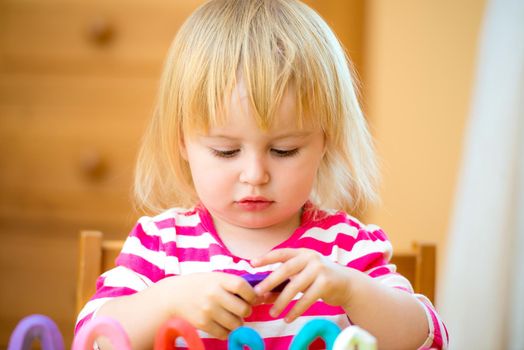 Little girl playing with plasticine at home