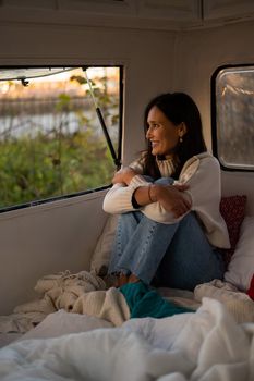 Pensive Caucasian woman in light sweater motorhome in warm autumn. Travel in a van