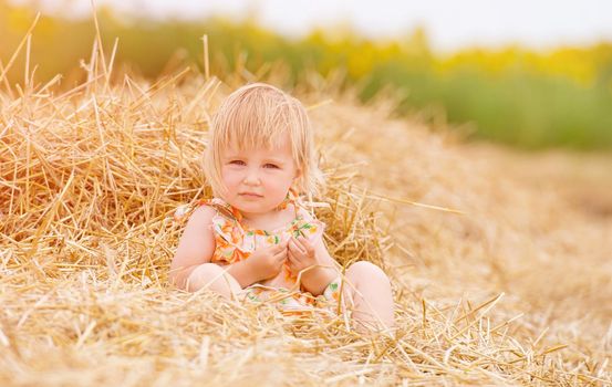 baby girl sitting in the hay