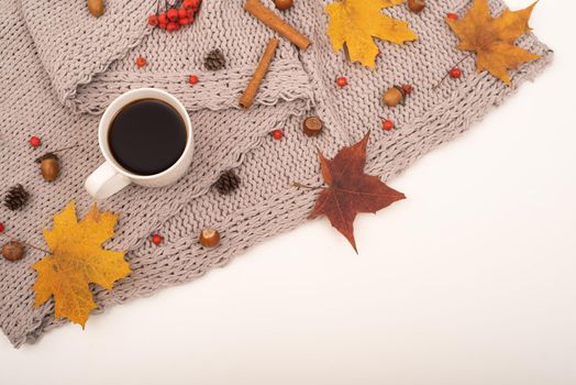 Autumn flat lay. Maple leaves, acorns and a cup of black coffee on a gray blanket. Copy space.