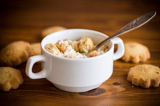 Homemade cottage cheese with pieces of shortbread cookies for breakfast, on a wooden table