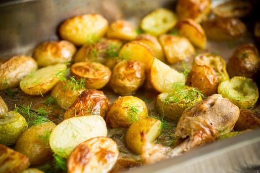 Early baked potatoes with zucchini and chicken, on a wooden table