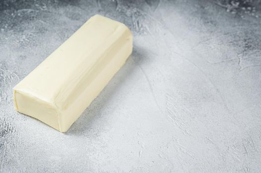 Piece of fresh butter for breakfast on kitchen table. White background. Top view. Copy space.