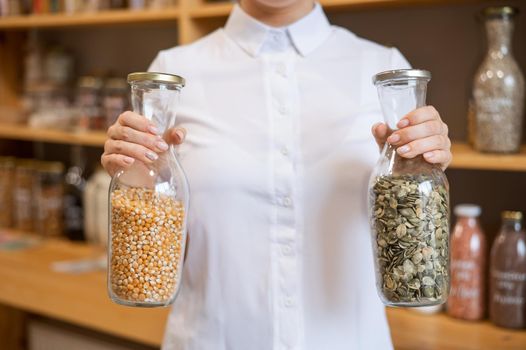 A woman holds two jars of cereals. Eco shop