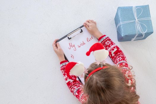 Christmas sale. Beautiful surprised child holding pen and writing.