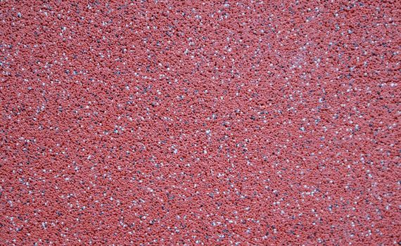 Colorful decorative mosaic plaster in burgundy or red. Wall texture, background. Granular, structured, rough, uneven textured coating. Modern exterior cladding