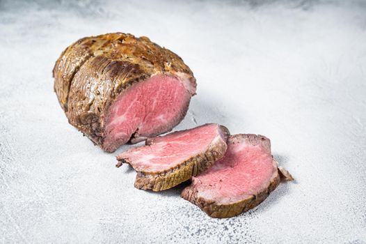 Roast beef meat fillet on kitchen table. White background. Top view.