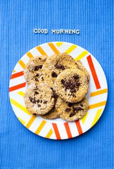 Oatmeal cookies with chocolate on blue napkin inscription good morning.