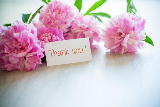 several branches of blooming pink peonies on a wooden background