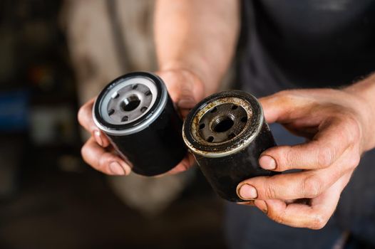 An auto mechanic holds a new and used oil filter