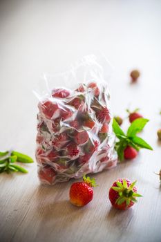 frozen fresh strawberries in a vacuum bag on a wooden table