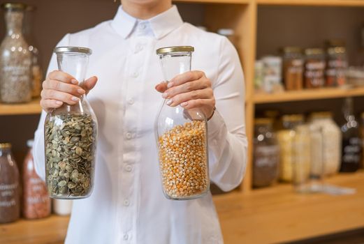 A woman holds two jars of cereals. Eco shop