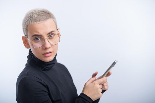Young caucasian woman with short hair uses a smartphone on a white background