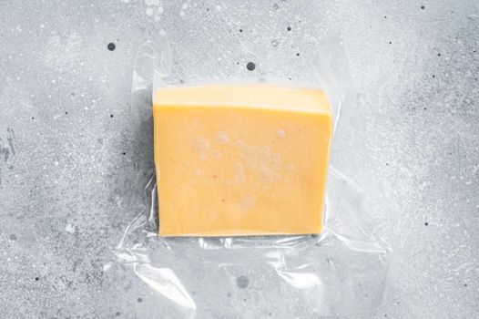 Organic Sharp Cheddar Cheese in vacuum packaging. Gray background. Top view.