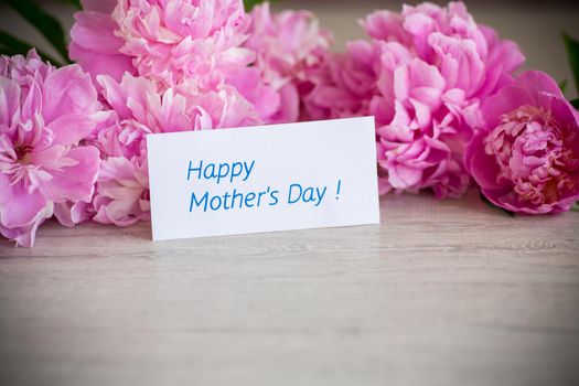 several branches of blooming pink peonies on a wooden background