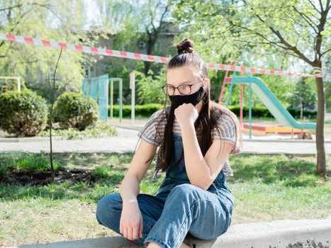 Portrait of a teenage girl on the background of the closed Playground in the period of quarantine.