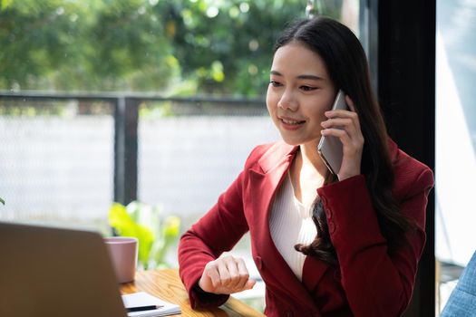 Asian employee talking with speaker phone and video call by smartphone in home office. Business financial concept