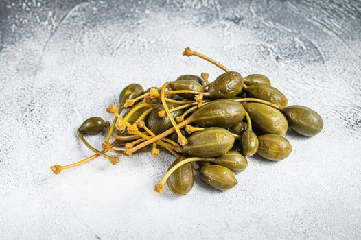 Pickled capers on a kitchen table. White background. Top view.