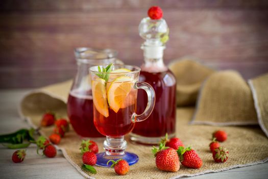 refreshing cool strawberry lemonade with lemon, ice and mint in a glass on a wooden table
