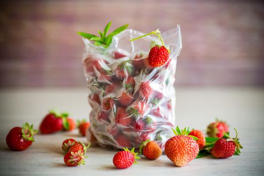 frozen fresh strawberries in a vacuum bag on a wooden table