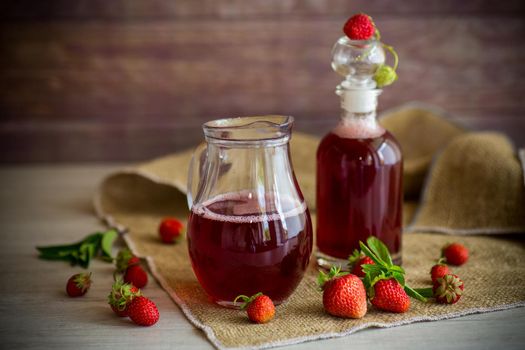 sweet cooked strawberry syrup in a glass decanter on a wooden table