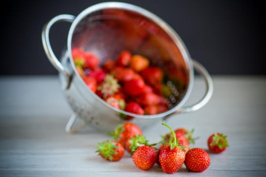 harvest of red ripe natural strawberries on a wooden table