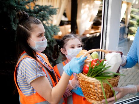 Teen girls in protective masks deliver a basket of food during the quarantine, the people who are on isolation.