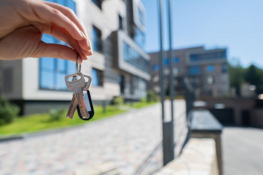 A woman holds the keys to a new house. Close-up of a female hand. Buying a property