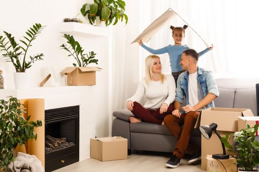 Happy family sitting on wooden floor. Father, mother and child having fun together. Moving house day, new home and design interior concept