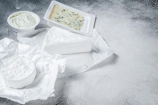 Variety of cheese kinds on kitchen table, brie, Camembert, Gorgonzola and blue creamy cheese. White background. Top view. Copy space.