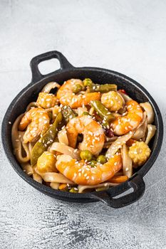 Udon stir-fry noodles with shrimps prawns in a pan. White background. Top view.