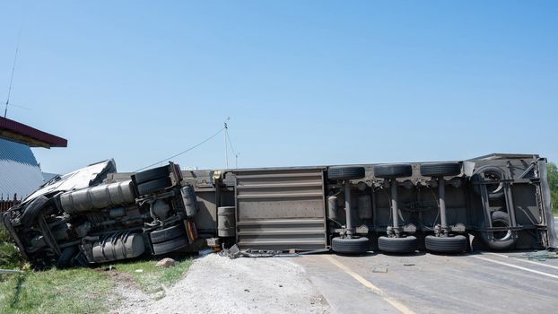 The truck is lying on its side in a car accident on the highway.