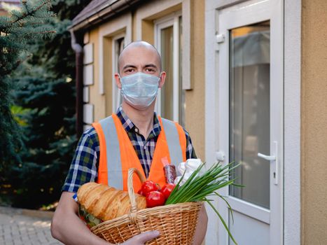 Volunteer work on food delivery during the coronavirus pandemic. Portrait of a man holding a basket of food.