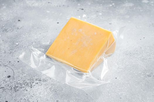 Organic Sharp Cheddar Cheese in vacuum packaging. Gray background. Top view.