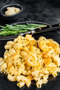 Baked Macaroni Mac and cheese American dish with Cheddar cheese sauce. Black background. Top view.