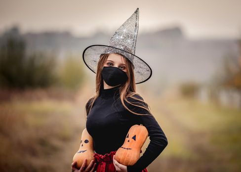 halloween portrait of teenage girl in medical mask with pumpkin