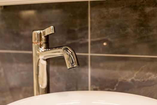 Luxury faucet mixer and white towel on a white sink in a beautiful gray bathroom. Sanitary prevention antivirus concept.