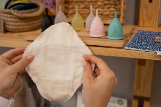 A woman in an eco store chooses a reusable pad. Intimate hygiene products.