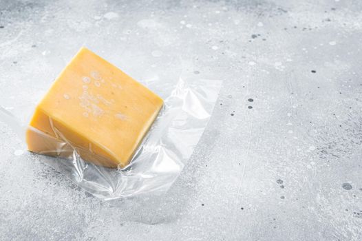 Organic Sharp Cheddar Cheese in vacuum packaging. Gray background. Top view. Copy space.