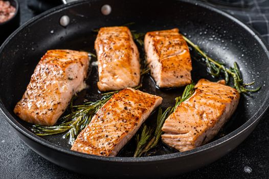 Roasted Salmon Fillet Steak in a pan with rosemary. Black background. Top view.