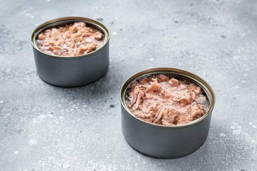 Open tin can with canned tuna fish. Gray background. top view.